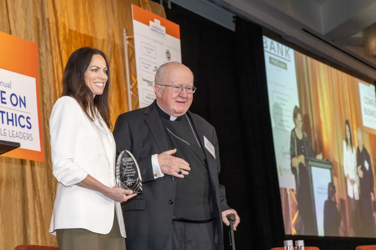 Laura K. Meier, Esq. with Bishop Kevin W. Vann, holding the Bishop's Award for Exemplary Business Integrity, at the 2026 Conference on Business & Ethics